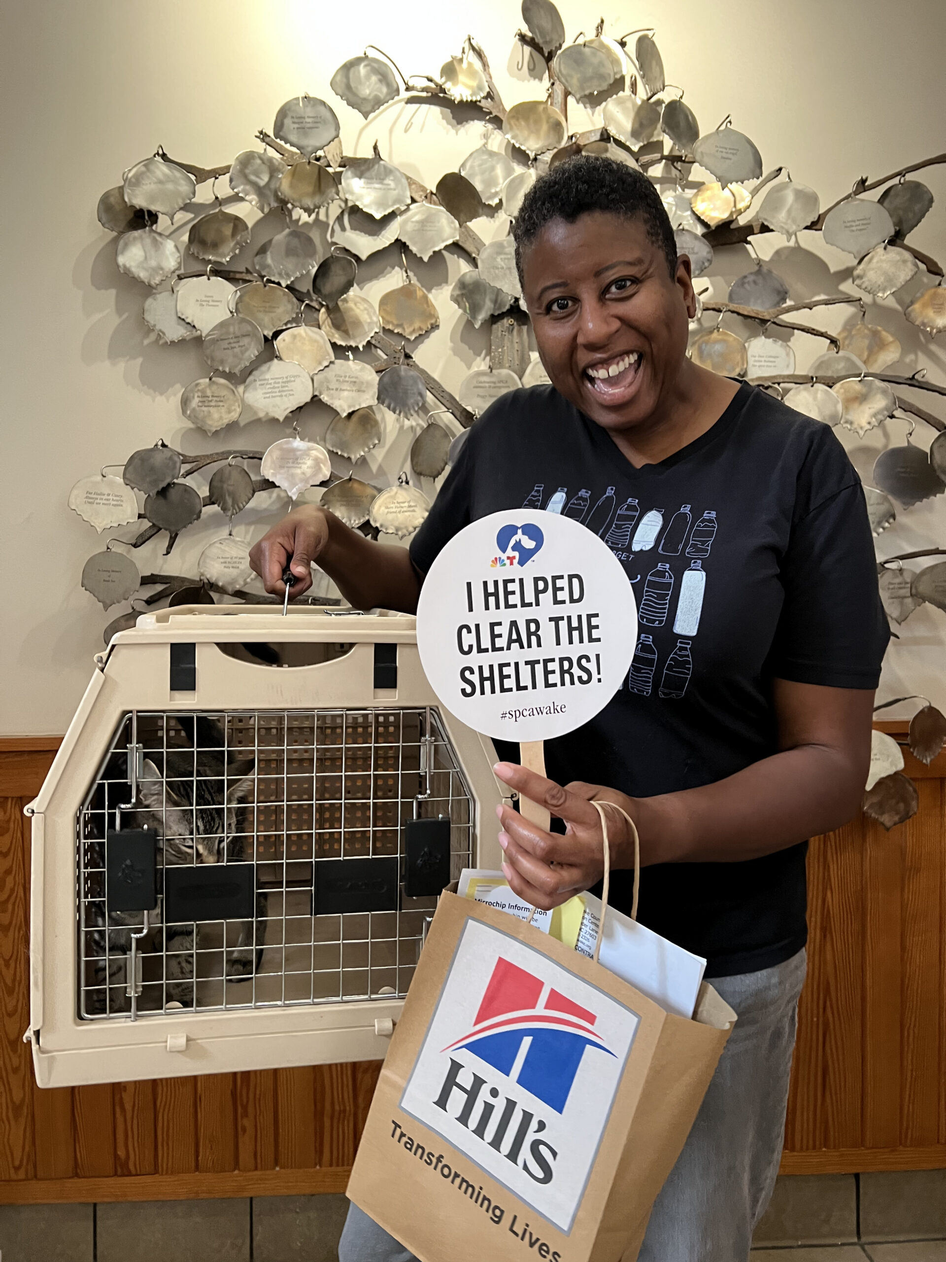 Smiling woman with a cat in a carrier adopted during the Clear the Shelters event