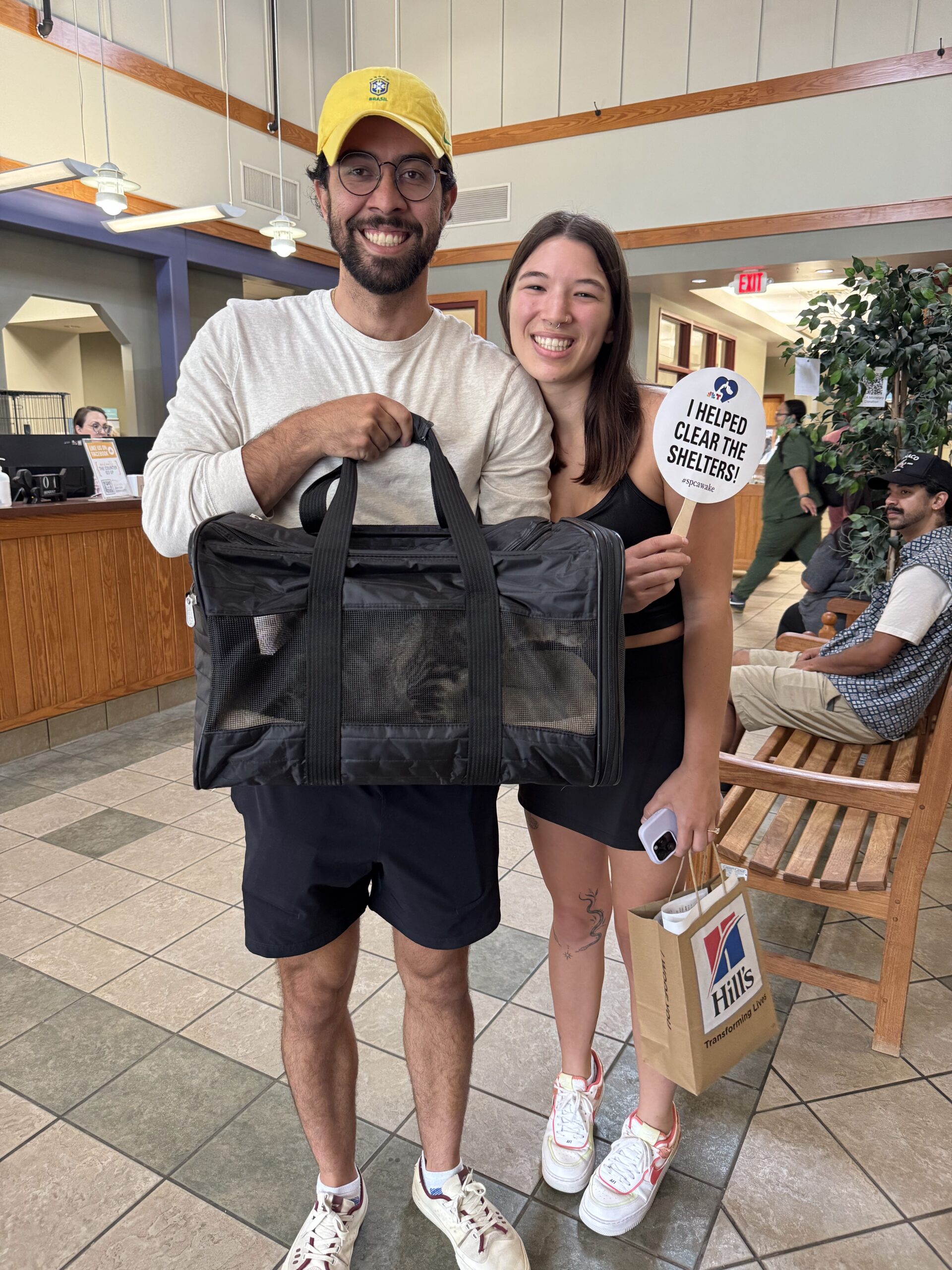 Happy couple with their cat in a carrier celebrate their adoption at Clear the Shelters